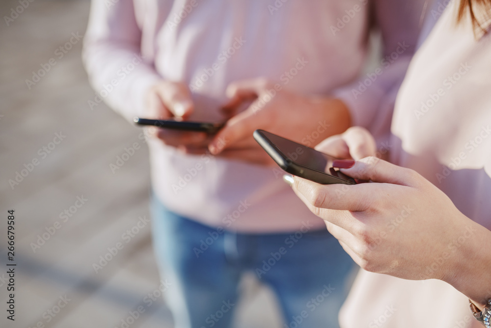 Close up of young caucasian couple using smart phones outdoors.