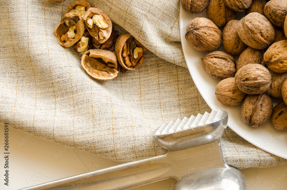 Plate with tasty walnuts and hammer on white background Plate with tasty walnuts and hammer on white background