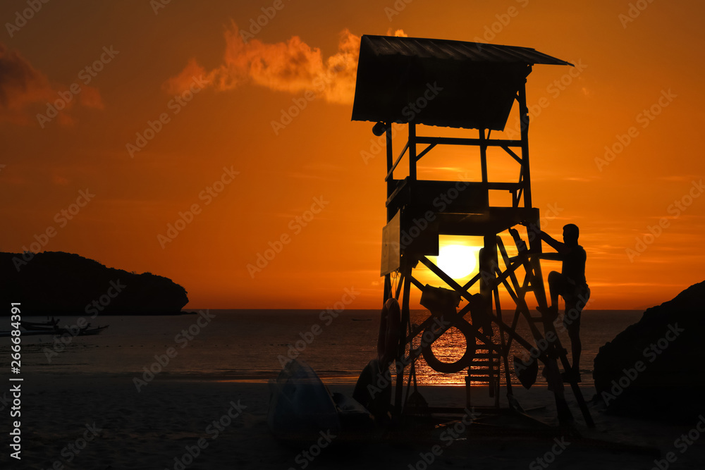 Lifeguard ready to take care of tourists on the beaches. Asian Lifeguard standing on the tower at sunrise