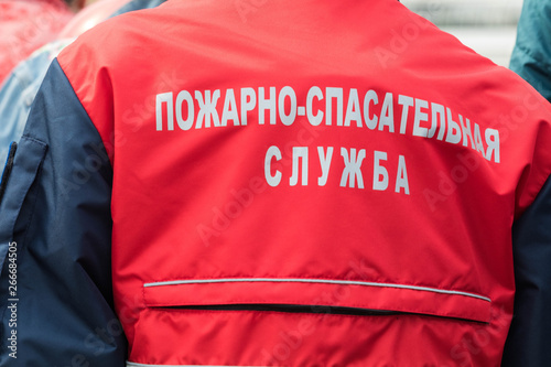  The man in a red jacket of special rescue services. On a back the inscription "Fire Rescue Services". View from a back, close up