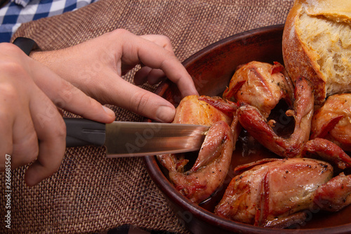 Man cuts roasted bird. Carving roasted bird. Kitchen knife in man’s hands. photo