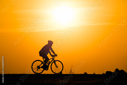 Silhouette man cycling on sunset background