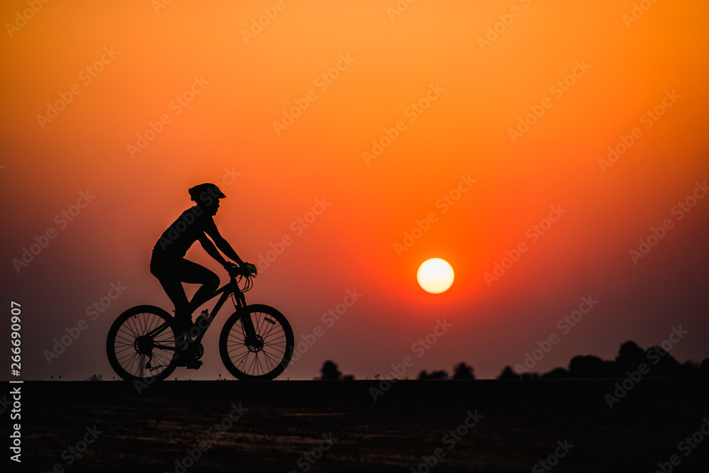 Fototapeta premium Silhouette man cycling on sunset background