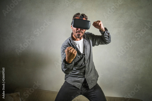 excited man wearing virtual reality VR goggles headset experimenting 3d illusion playing fight or boxing video game enjoying punching isolated on grunge background