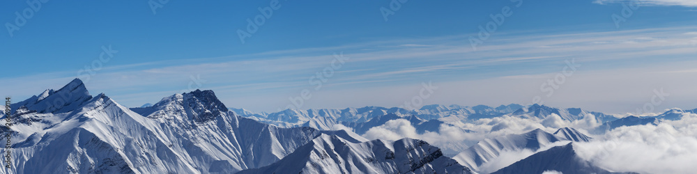 Panoramic view of snowy mountains and blue sky with clouds