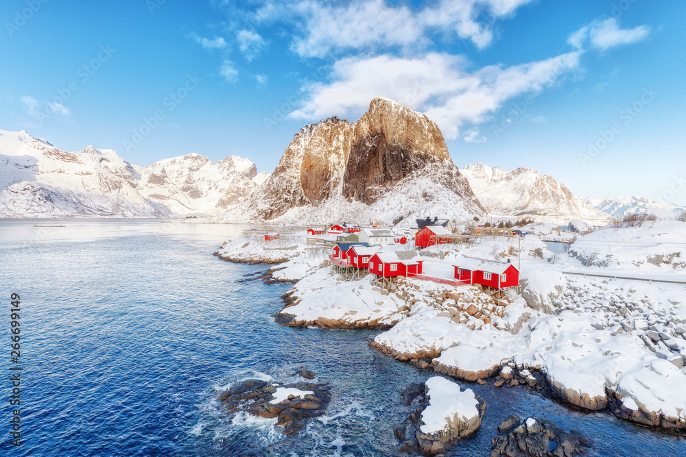 Norway, Hamnoy village on Lofoten islands. Spectacular view of traditional red fisherman Rorbuer cabins in stunning natural environment of northern sea and mountain peaks.