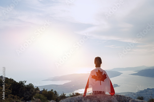 Photography Child teenager girl sitting on the top of the mountain with an Canadian flag on her shoulders