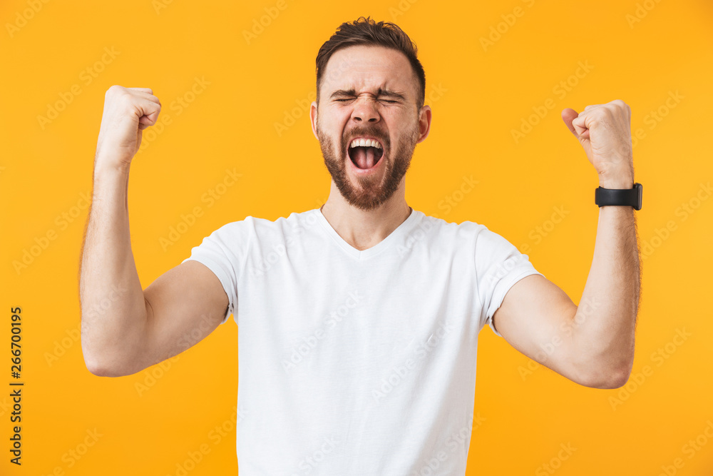 Fototapeta premium Man posing isolated over yellow wall background make winner gesture.
