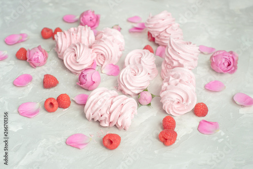 Homemade marshmallow with powdered sugar raspberries roses on gray concrete background