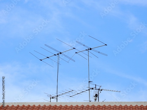 TV antenna on roof of home with blue sky