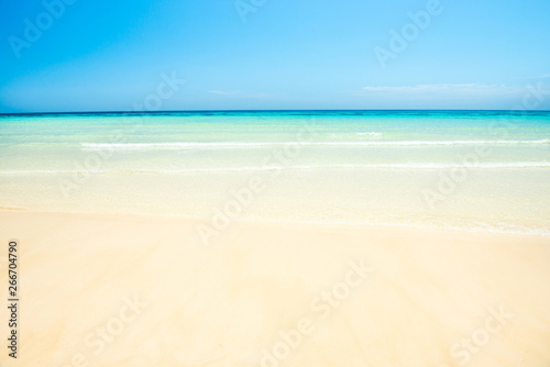 White sand beach and clear sea water under blue sky