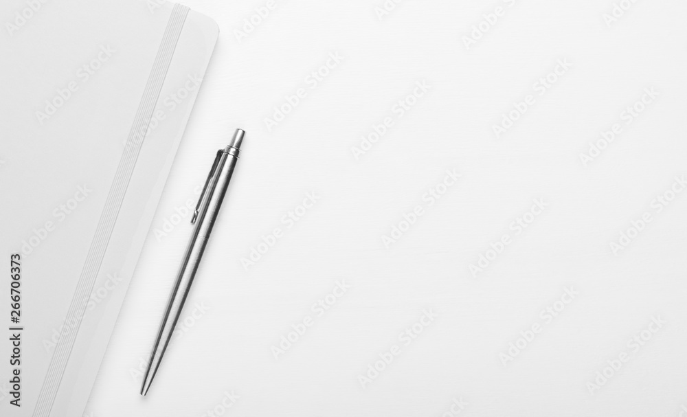 White notepad with steel pen on a white wooden background. Minimal composition, save space, top view, flat lay. White notepad with steel pen on a white wooden background. Minimal composition, save space, top view, flat lay.