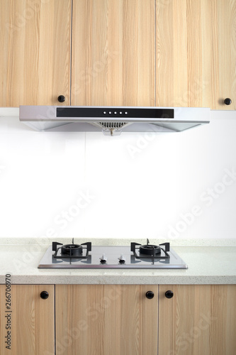 Cooking gas stove with hood in modern kitchen, pantry. top and bottom wood cabinets.