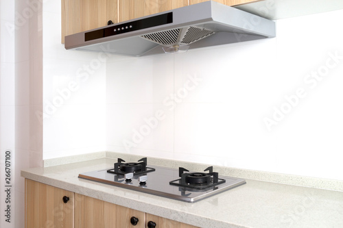 Cooking gas stove with hood in modern kitchen, pantry. top and bottom wood cabinets.