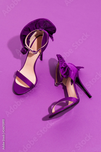 Purple high heels on violet monochrome backgroung with bows