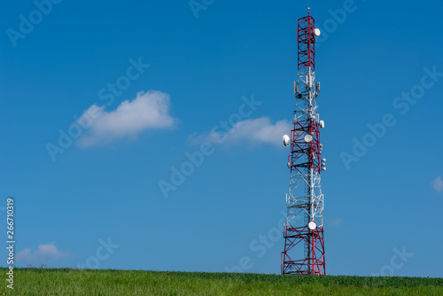 Telecommunication tower on the green field against clean blue sky