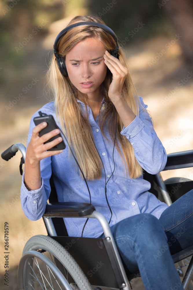 girl on the wheelchair holding a cellular phone girl on the wheelchair holding a cellular phone