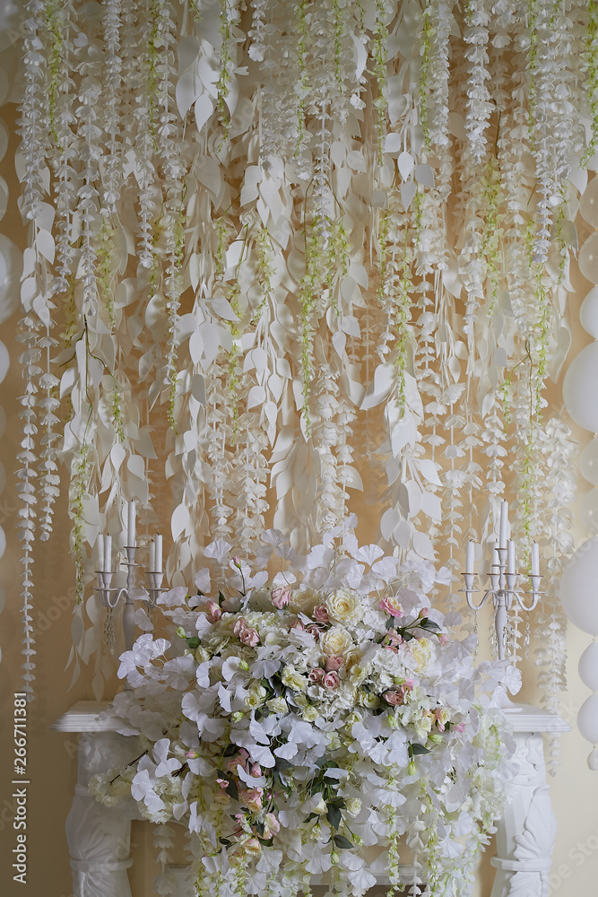 Flower garland on the wall as an element of festive, wedding decor. Light tone. Decorative fireplace. Flower garland on the wall as an element of festive, wedding decor. Light tone. Decorative fireplace.