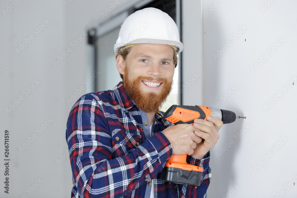 male carpenter using drill on wall