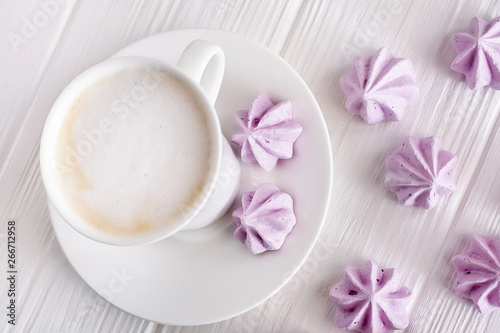 white cup of coffee, cappuccino on a white background with lilac meringues