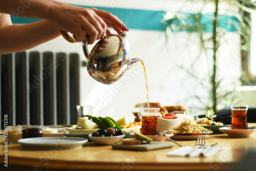 Female hand pouring tea into turkish glass