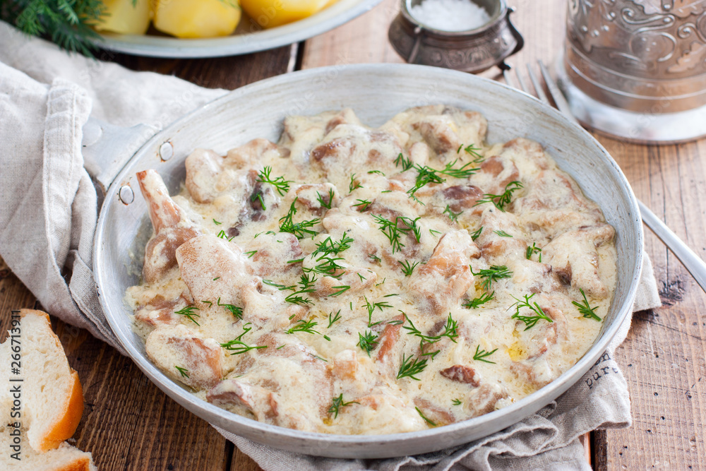 Forest mushrooms in sour cream sauce on a pan on a wooden table, horizontal Forest mushrooms in sour cream sauce on a pan on a wooden table, horizontal