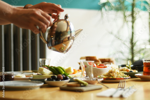 Female hand pouring tea into turkish glass