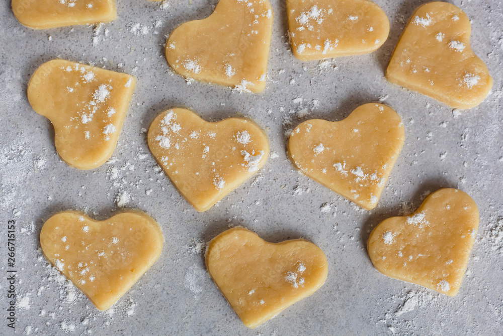 Raw dough cookies in the shape of hearts. The process of making cookies and gingerbread at home. pattern close-up Raw dough cookies in the shape of hearts. The process of making cookies and gingerbread at home. pattern close-up