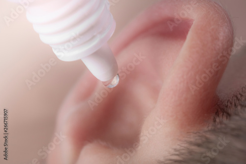 Medical pipette with a drop of medication over the patient's ear