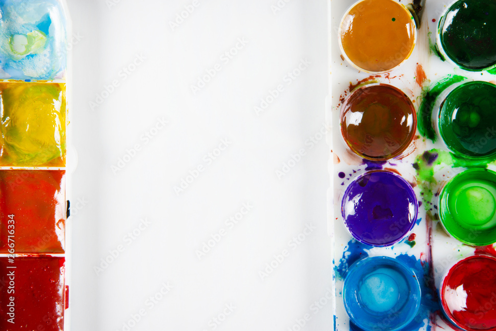 A set of children's paints in round, rectangular forms close-up. Copy space for text In frame