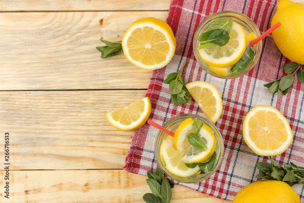 Homemade lemonade with mint and lemon in plastic glasses on a natural wooden background. Refreshing lemonade drink. top view Homemade lemonade with mint and lemon in plastic glasses on a natural wooden background. Refreshing lemonade drink. top view
