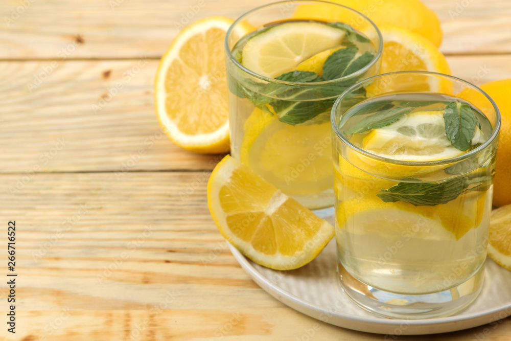 Homemade lemonade with mint and lemon in plastic glasses on a natural wooden background. Refreshing lemonade drink. Homemade lemonade with mint and lemon in plastic glasses on a natural wooden background. Refreshing lemonade drink.