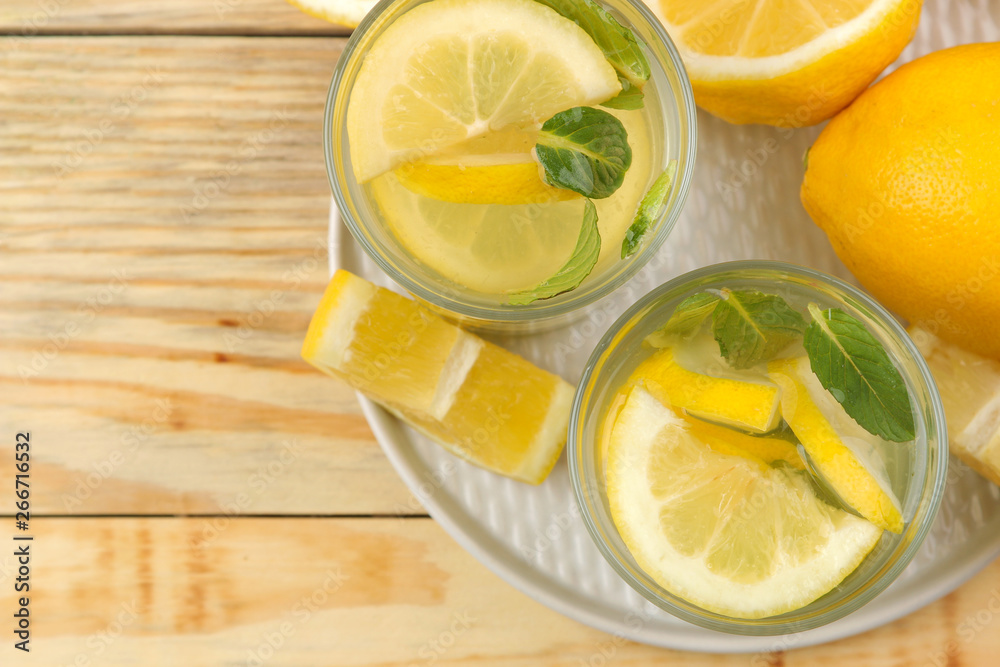 Homemade lemonade with mint and lemon in plastic glasses on a natural wooden background. Refreshing lemonade drink. top view Homemade lemonade with mint and lemon in plastic glasses on a natural wooden background. Refreshing lemonade drink. top view