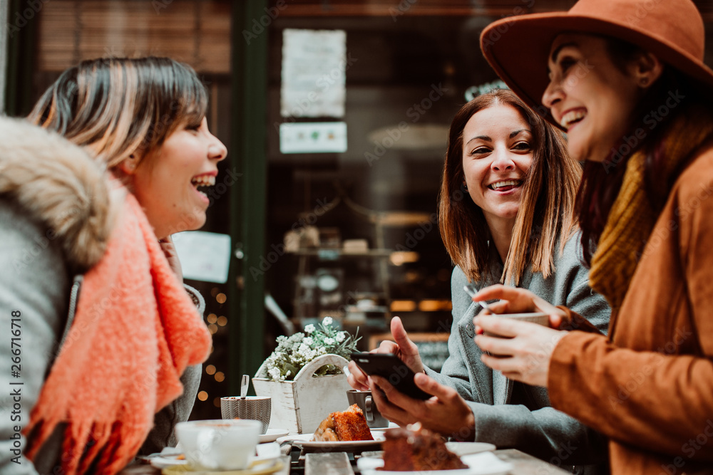 .Group of young friends drinking coffee with cakes in an outdoor cafe in Porto, Portugal. Talking and laughing together. Lifestyle. Travel photography