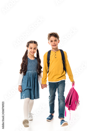 full length view of schoolchildren with backpacks holding hands isolated on white