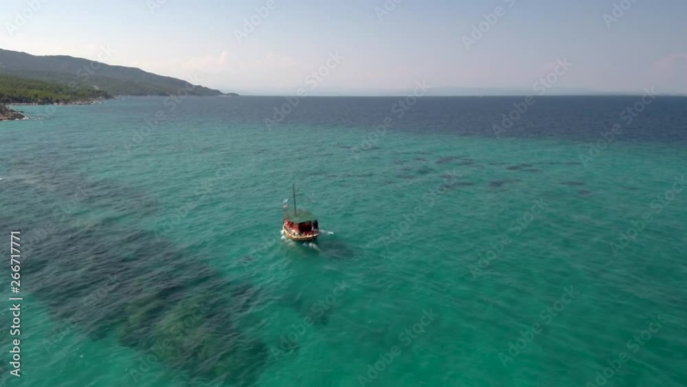 Aerial view of tourist boat in turquoise sea in Kavourotripe in Halkidiki Greece, move forward by drone Aerial view of tourist boat in turquoise sea in Kavourotripe in Halkidiki Greece, move forward by drone