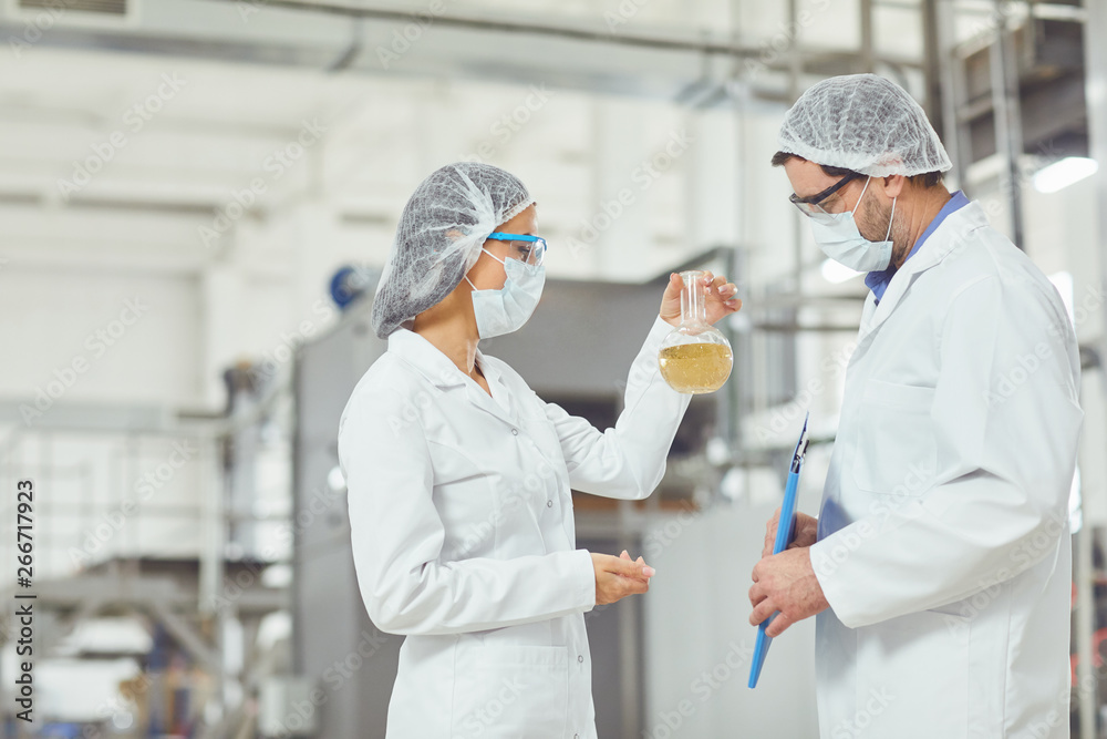 Technologist in masks and coats look at the liquid Technologist in masks and coats look at the liquid