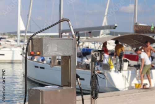 Fuel distributor on the pier of a gas station in the Mediterranean marina against the backdrop of sailing yachts. Refualing boats and fishing boats. Infrastructure of the Adriatic port. Saturday