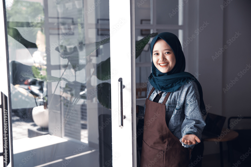 muslim cafe worker greeting customer at front door muslim cafe worker greeting customer at front door
