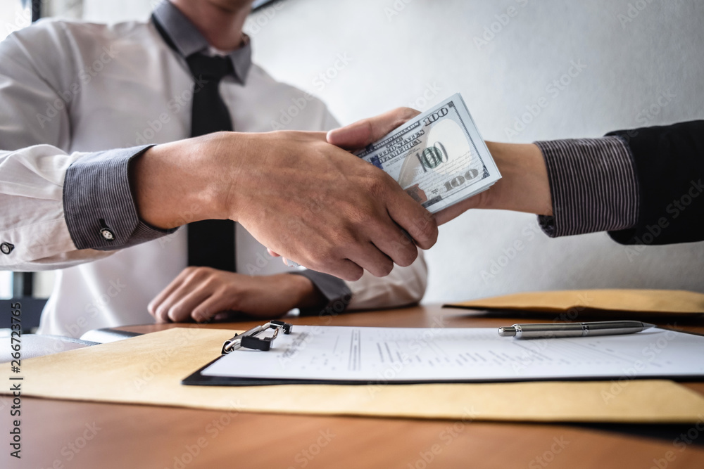 Dishonest cheating in business illegal money, Businessman handshake with money of dollar banknotes in hands from while give success the deal, Bribery and corruption concept Dishonest cheating in business illegal money, Businessman handshake with money of dollar banknotes in hands from while give success the deal, Bribery and corruption concept