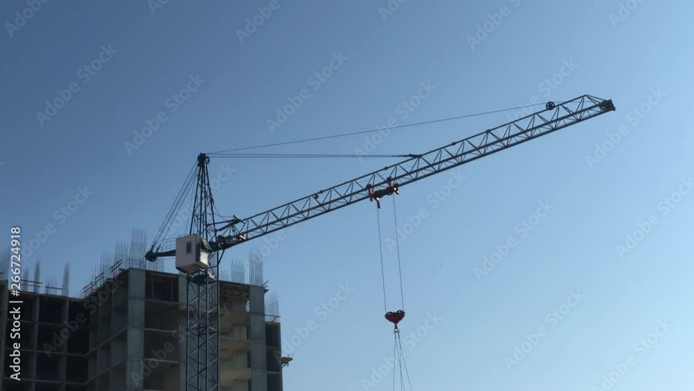 Construction crane turns the arrow on the background of construction and the sky Construction crane turns the arrow on the background of construction and the sky