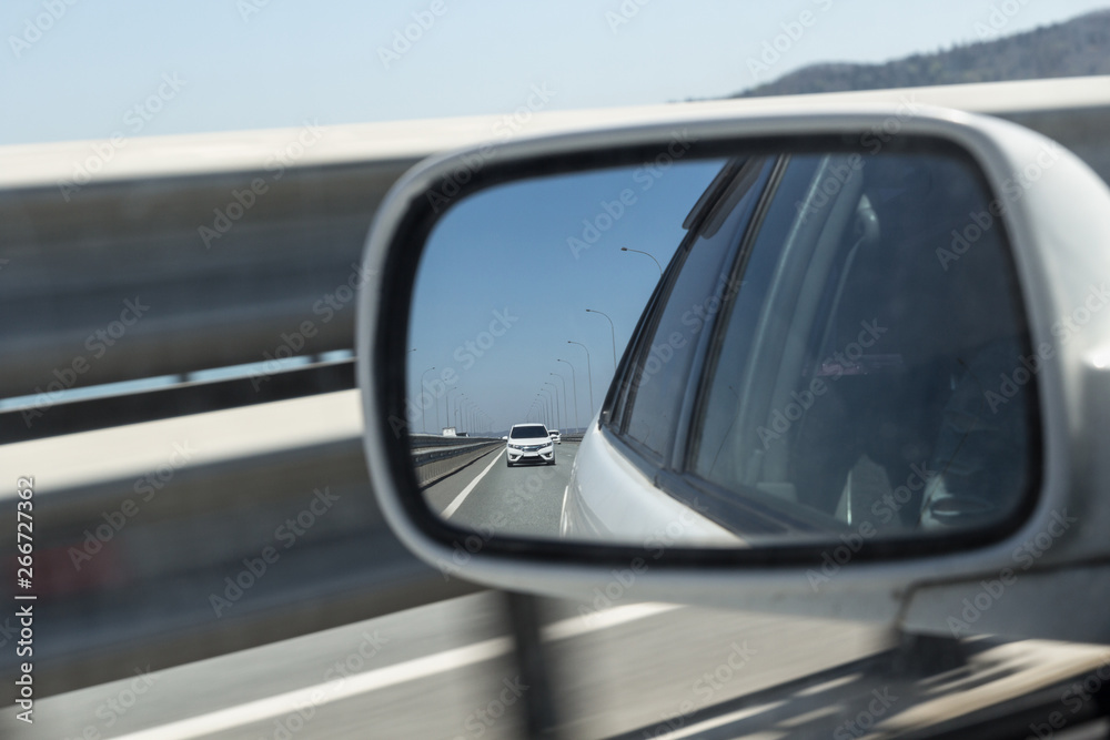 View in the side mirror of the car. Another car goes to overtake