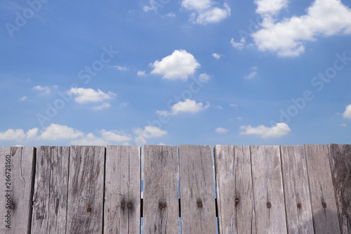 Old wooden fence with bright sky and clouds.