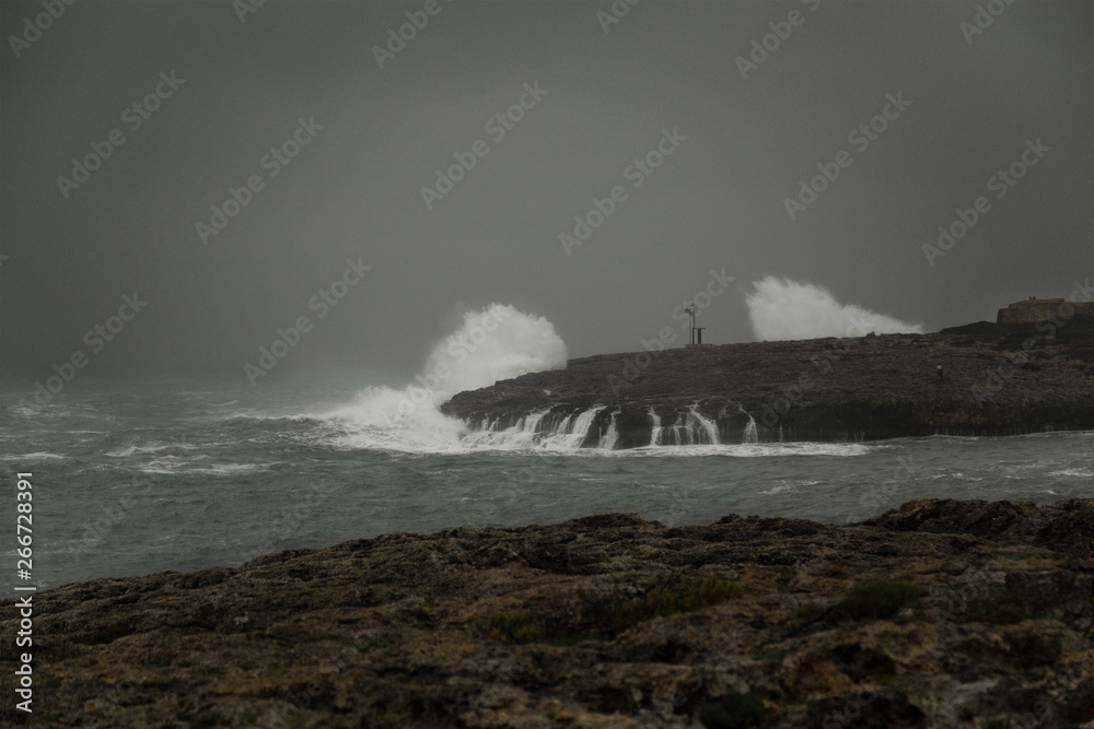 Lighthouse on the coast during stormy weather and big waves.