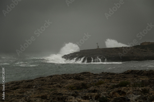 Lighthouse on the coast during stormy weather and big waves.