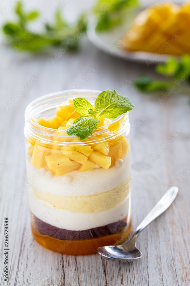 Sweet homemade Mango dessert, cheesecake, trifle, mouse in a glass jar on a light wooden background, vertical composition Sweet homemade Mango dessert, cheesecake, trifle, mouse in a glass jar on a light wooden background, vertical composition