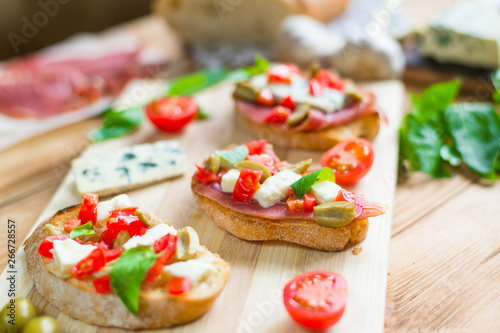 Toasted ciabatta, a cheese sandwich with mold, tomatoes, basil on a wooden background.