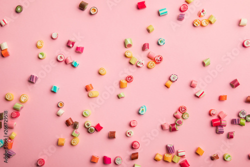 top view of delicious multicolored candies scattered on pink background