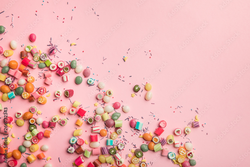 top view of colorful candies and sprinkles scattered on pink background with copy space top view of colorful candies and sprinkles scattered on pink background with copy space