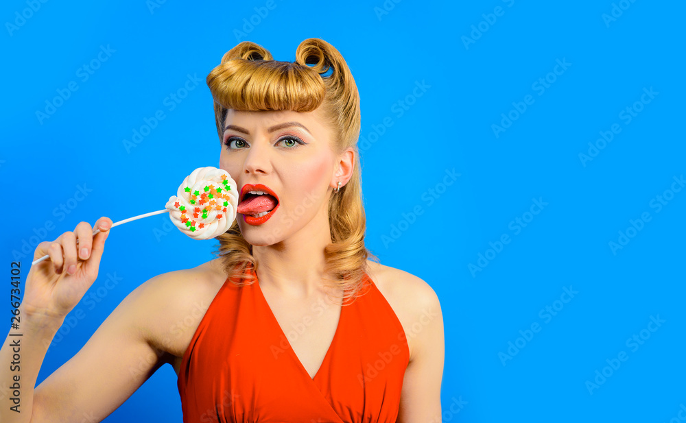 Charming pin-up woman with retro hairstyle and make-up licks lollipop.  Sensual woman with vintage makeup and hairdo holds lollipop. Sexy beautiful  girl eat big lollipop. Food, dessert, candy, sweets. Stock Photo